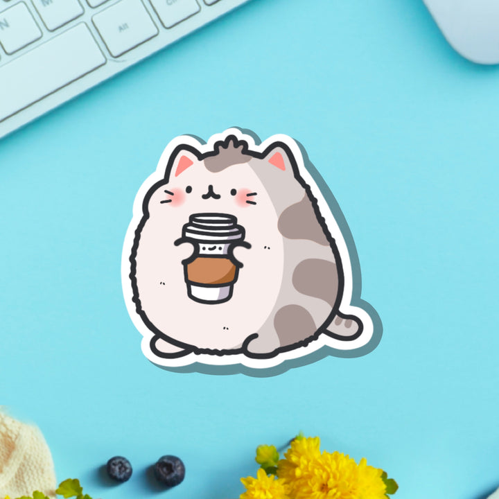 Cat holding coffee vinyl sticker on blue table with keyboard