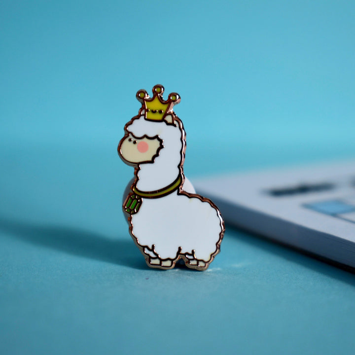 Llama enamel pin on blue table with notebook