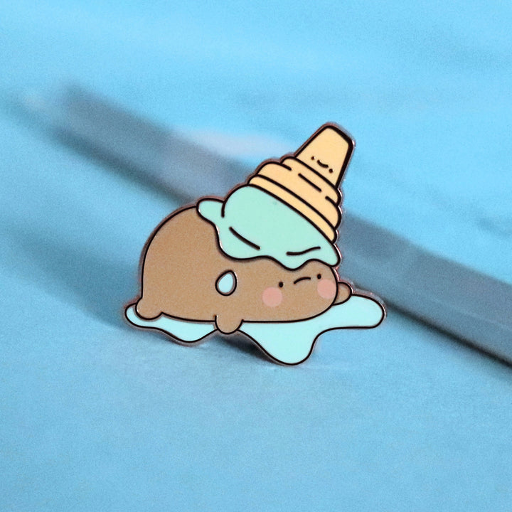 Potato in ice cream enamel pin on blue table with notepad