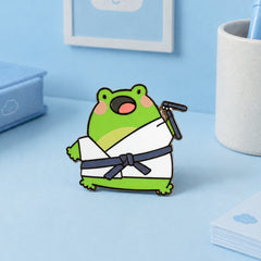 Karate frog enamel pin on blue desk with stationery