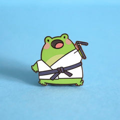Karate frog enamel pin on blue table