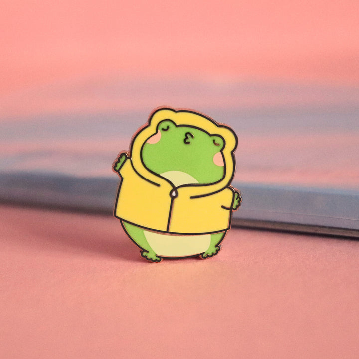 Kissing frog enamel pin on pink table