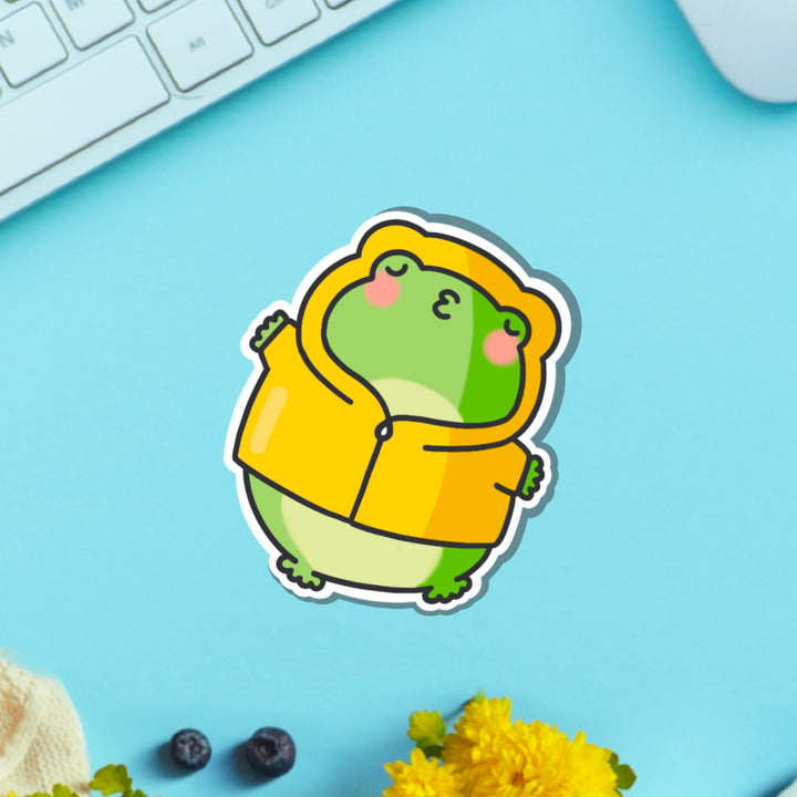 Kissing frog in yellow coat vinyl sticker on blue table with keyboard