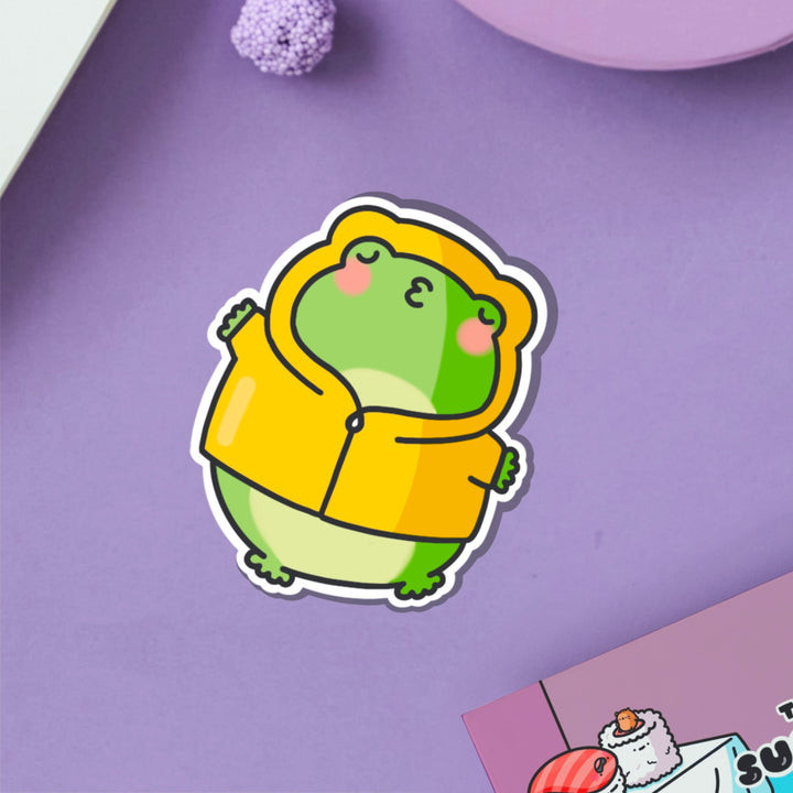 Kissing frog in yellow coat vinyl sticker on purple table