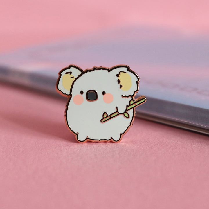 Koala enamel pin on pink table with notepad