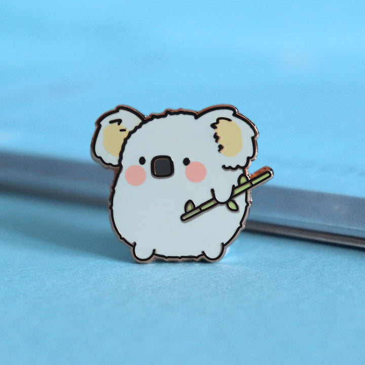 Koala enamel pin on blue table with notepad