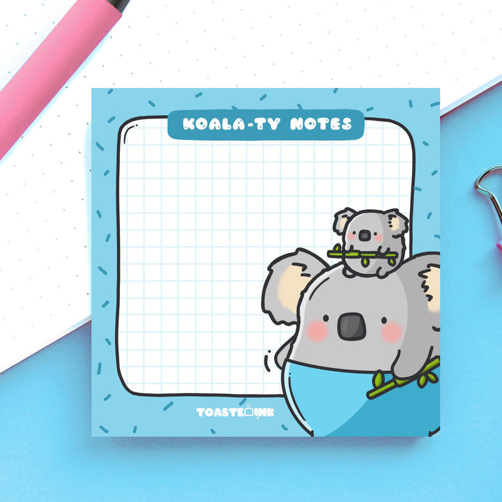 Koala sticky notes on blue and white table with pink pen