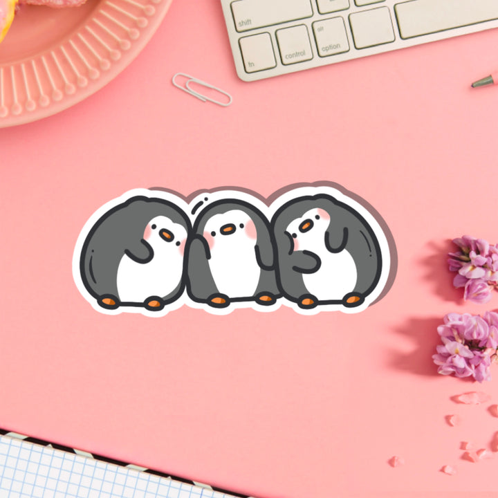 Three penguins in a line vinyl sticker on pink table