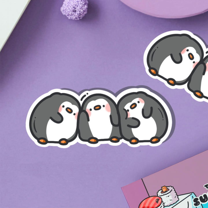 Three penguins in a line vinyl sticker on purple table