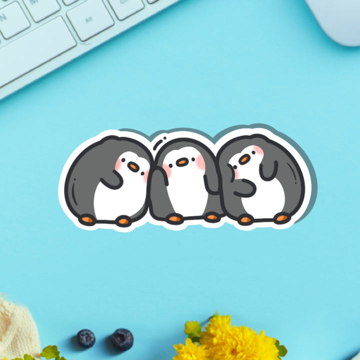Three penguins in a line vinyl sticker on blue table with keyboard