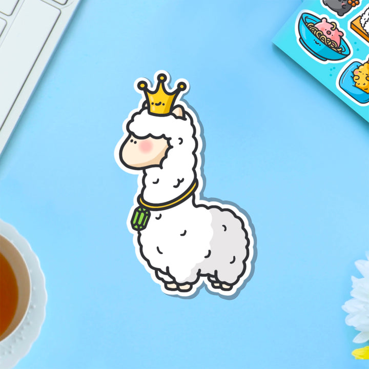 Llama wearing crown vinyl sticker on blue table