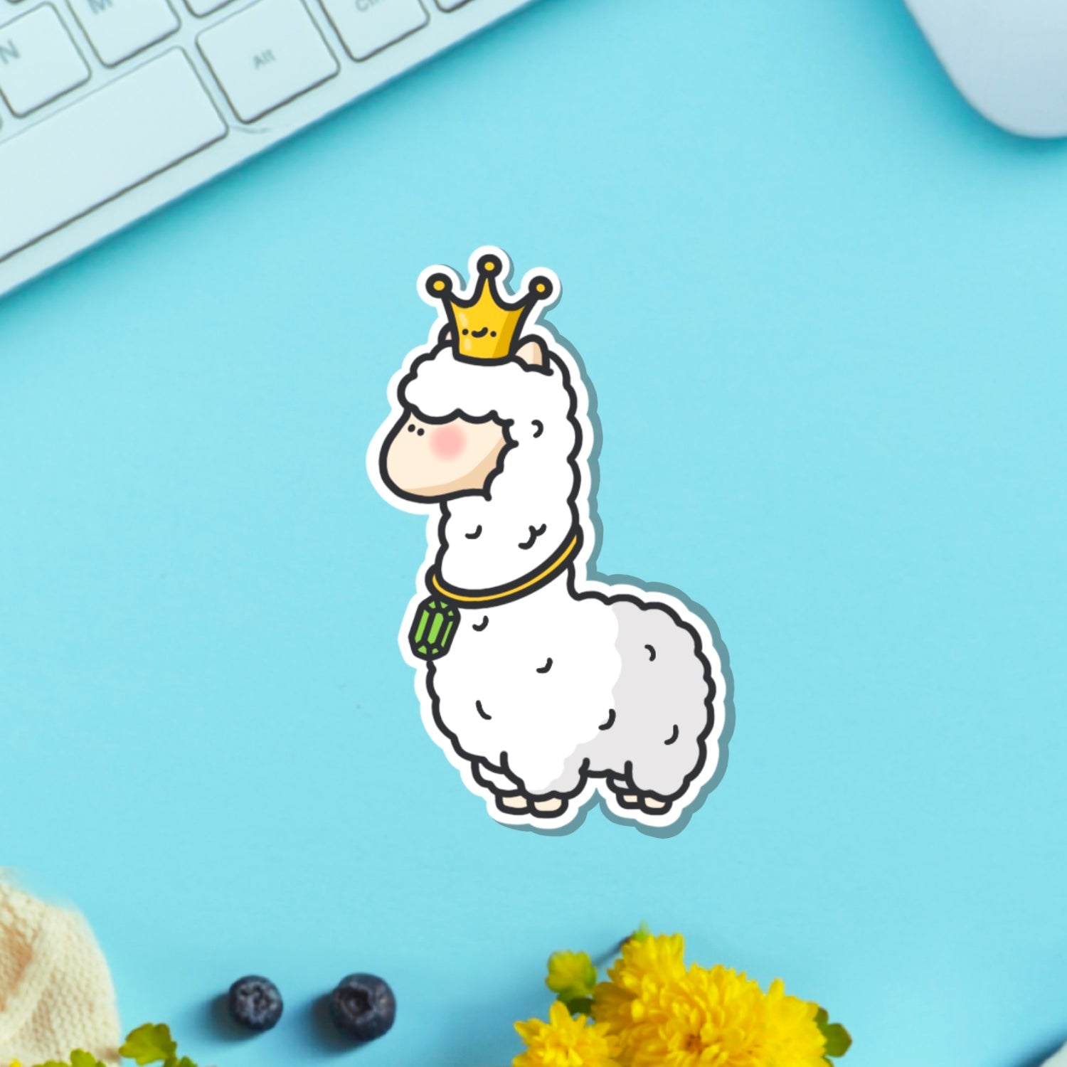 Llama wearing crown vinyl sticker on blue table with keyboard