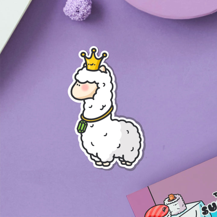 Llama wearing crown vinyl sticker on purple table