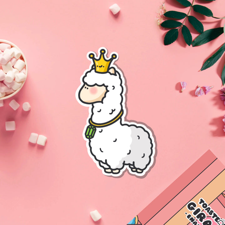 Llama wearing crown vinyl sticker on pink table