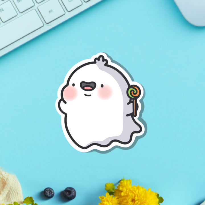Ghost holding lollipop vinyl sticker on blue table with keyboard