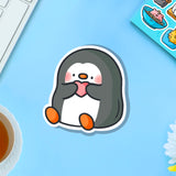 Penguin holding heart vinyl sticker on blue table