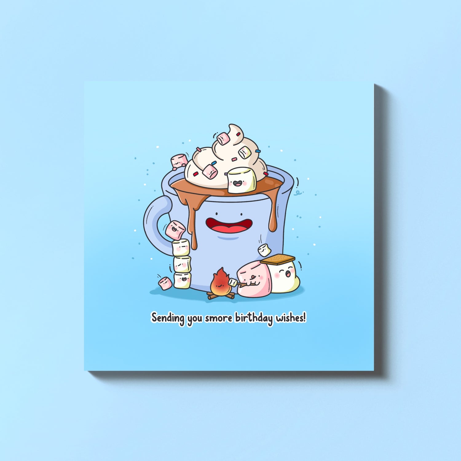 Cute hot chocolate mug with marshmallows and a toasting flame on a blue background, with text 'Sending you smore birthday wishes!'.