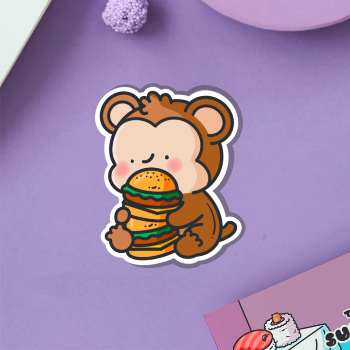 Monkey eating burgers vinyl sticker on purple table