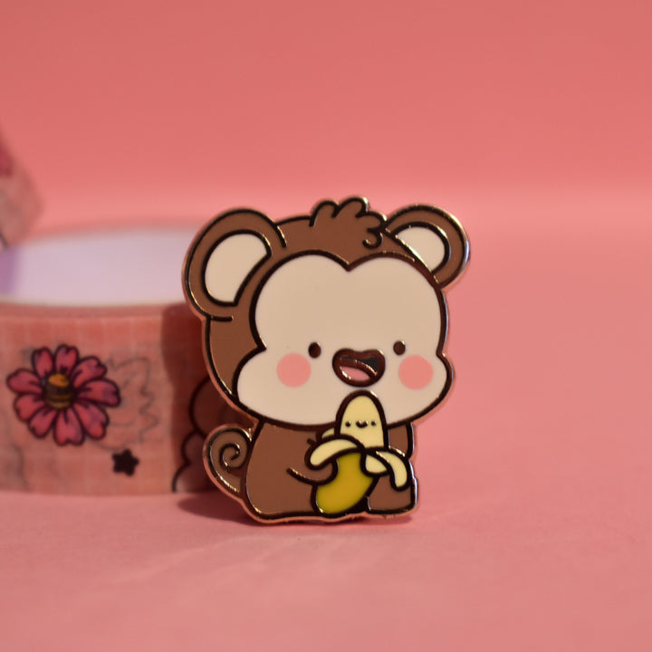 Monkey enamel pin on pink table with washi tape