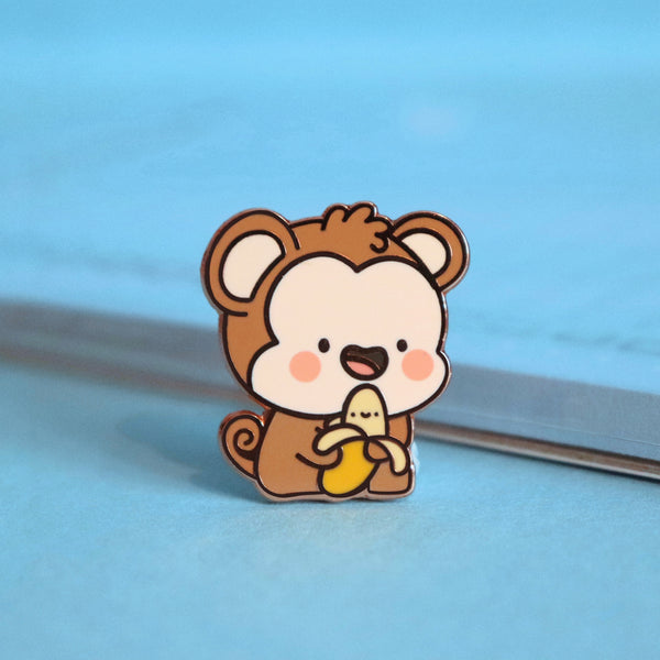 Monkey enamel pin on blue table with notepad