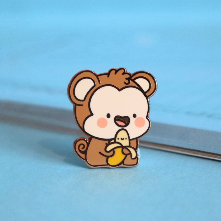 Monkey enamel pin on blue table with notepad