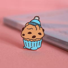 Muffin enamel pin on pink table with notepad