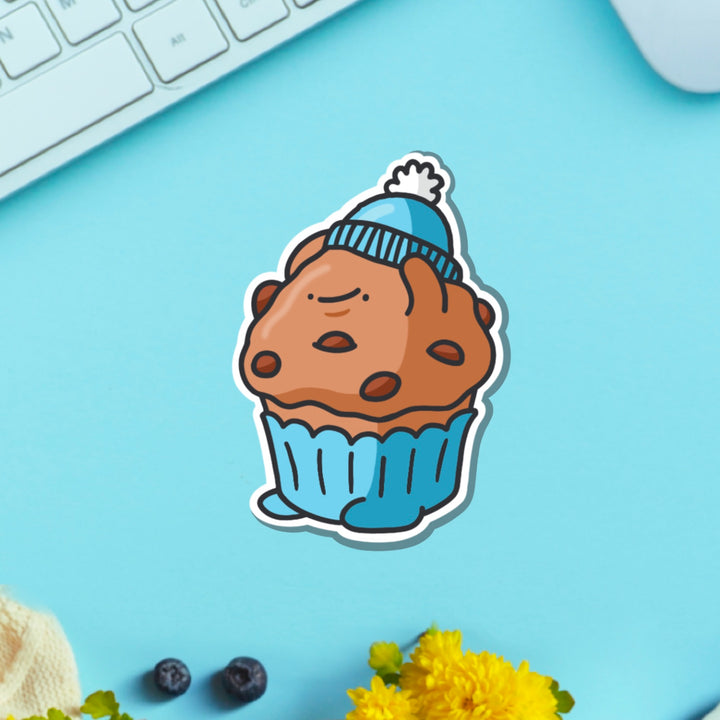 Muffin wearing hat vinyl sticker on blue table with keyboard