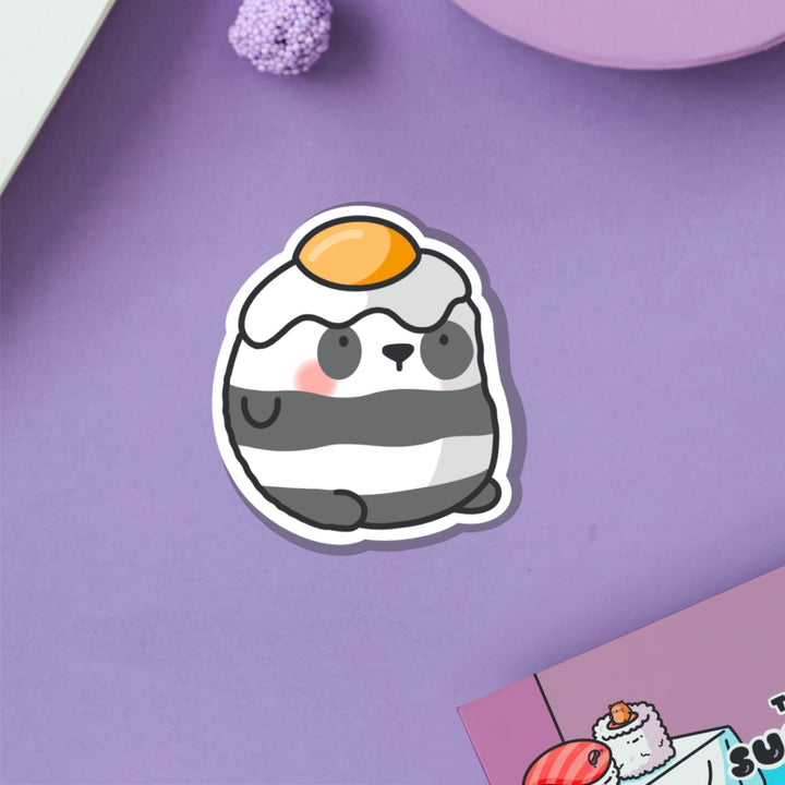 Panda with an egg on his head vinyl sticker on purple table