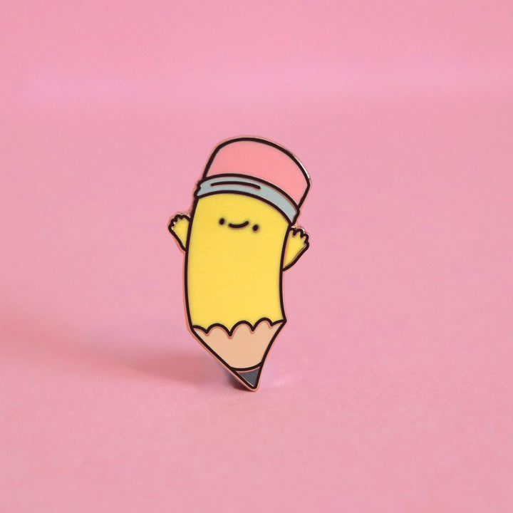 Pencil enamel pin on pink desk