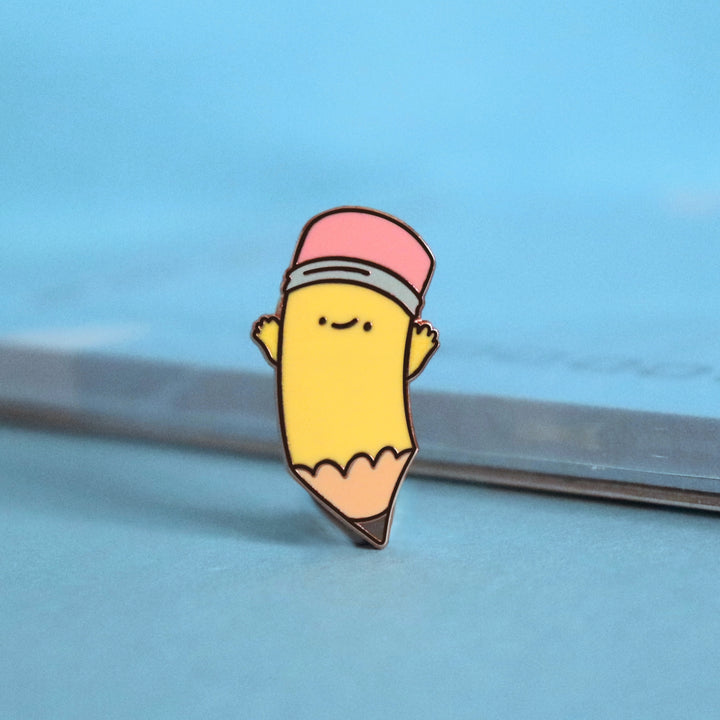 Pencil enamel pin on blue desk