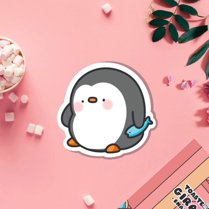 penguin holding fish vinyl sticker on pink table