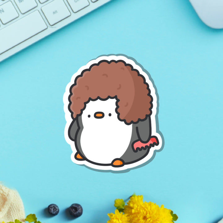 Penguin with hairdo vinyl sticker on blue table with keyboard