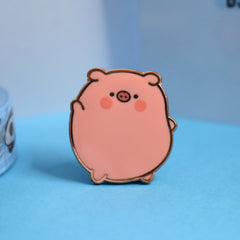Pig enamel pin on blue desk