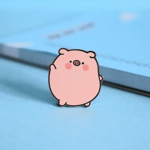 Pig enamel pin on blue table