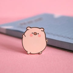 Pig enamel pin on pink table with notepad