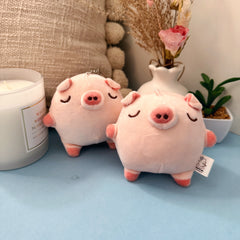 Two baby pig plush keychains on blue table