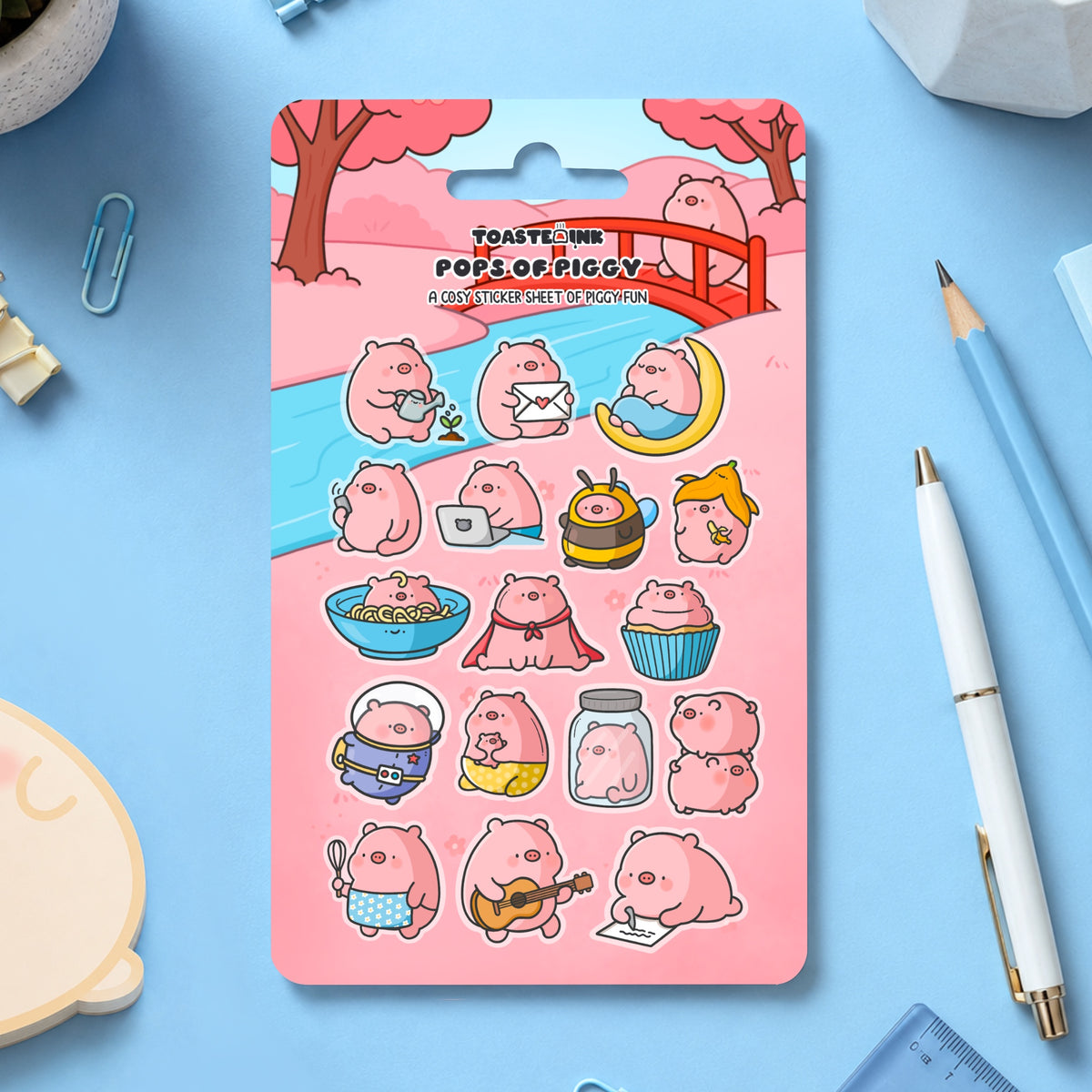 Pig sticker sheet on blue desk with scattered stationery