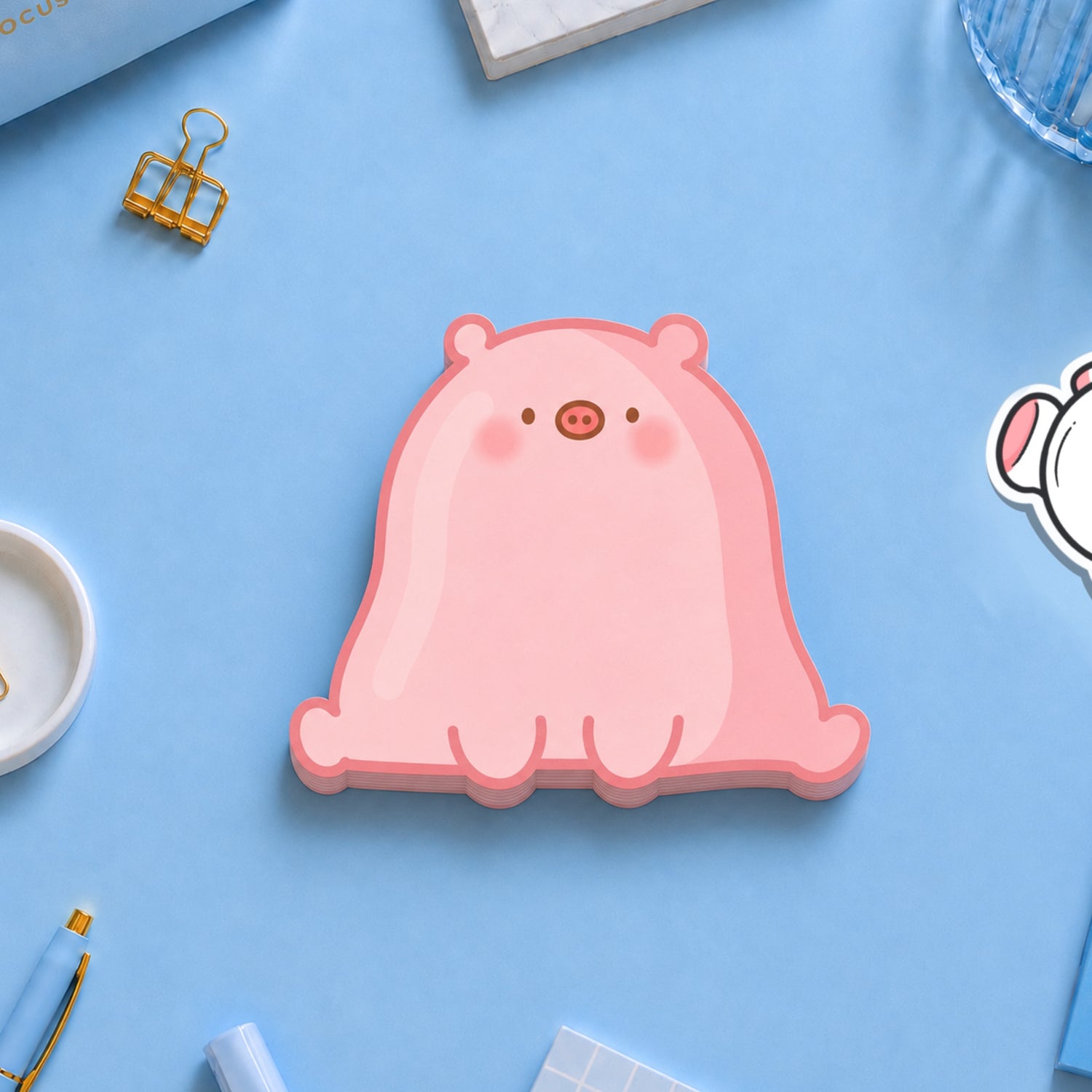 Pig shaped sticky notes on blue desk with stationery