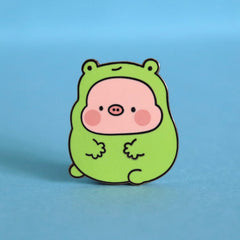 Pig in frog costume enamel pin on blue desk