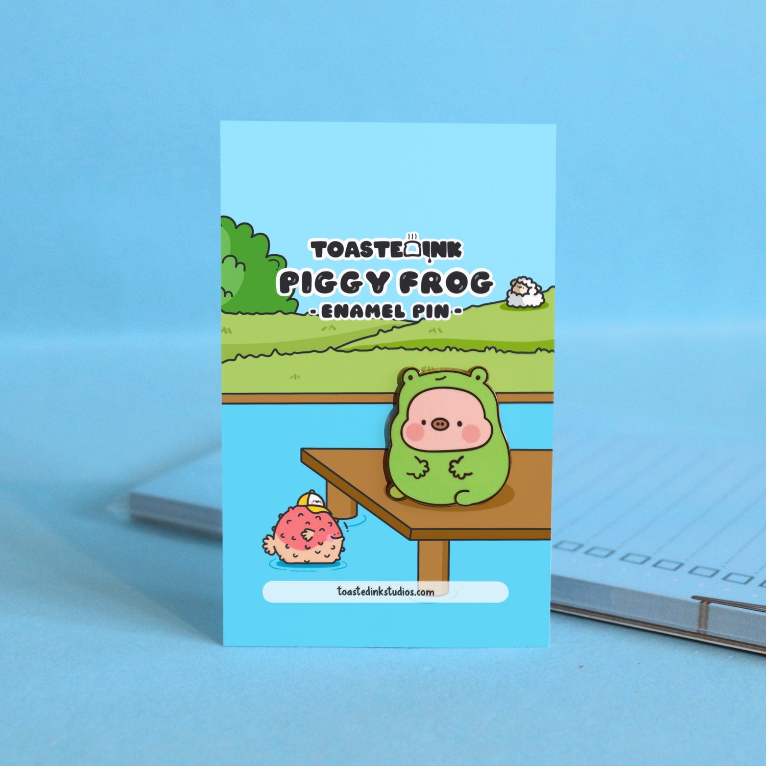 Pig in frog costume enamel pin on backing card