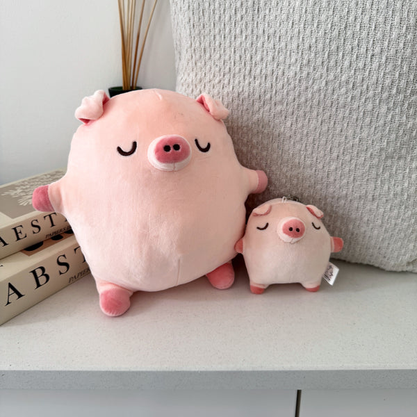 Pig plush and keychain plush on white table with cushion