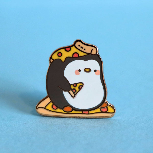 Penguin with pizza on his head enamel pin on blue table