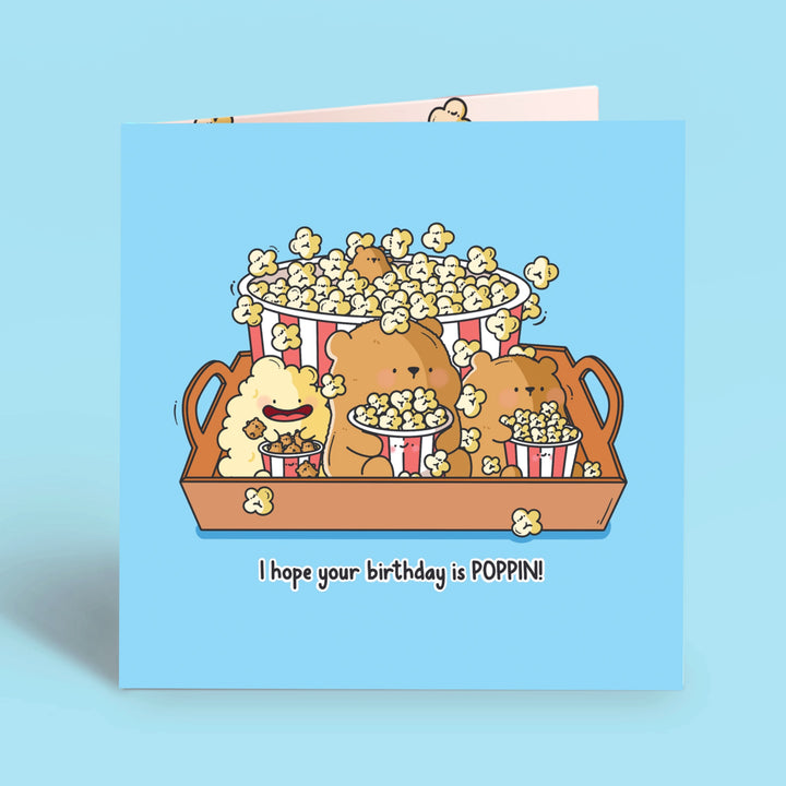 Bear with popcorn card on blue table