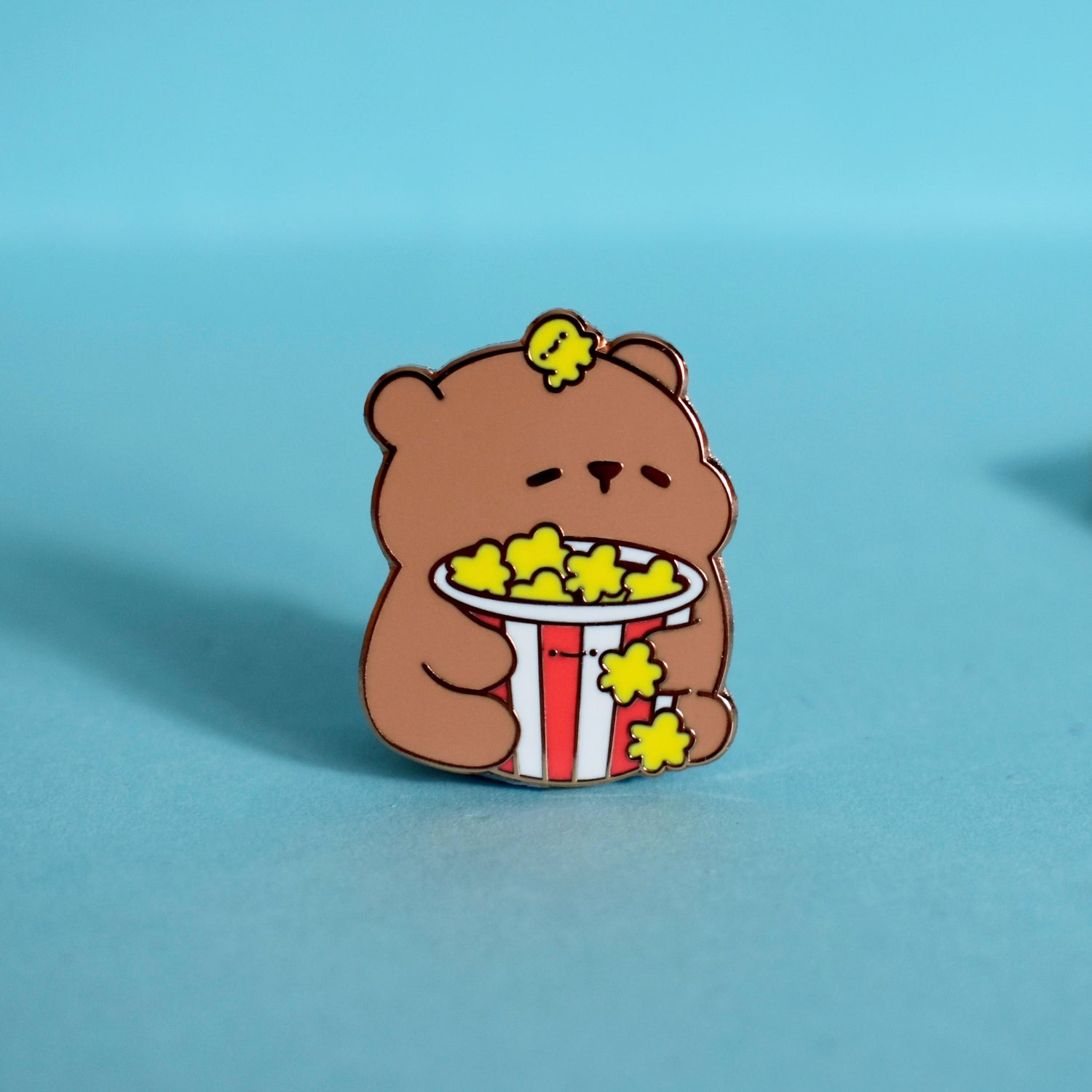 Bear with popcorn enamel pin on green desk