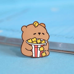 Bear with popcorn enamel pin on blue table