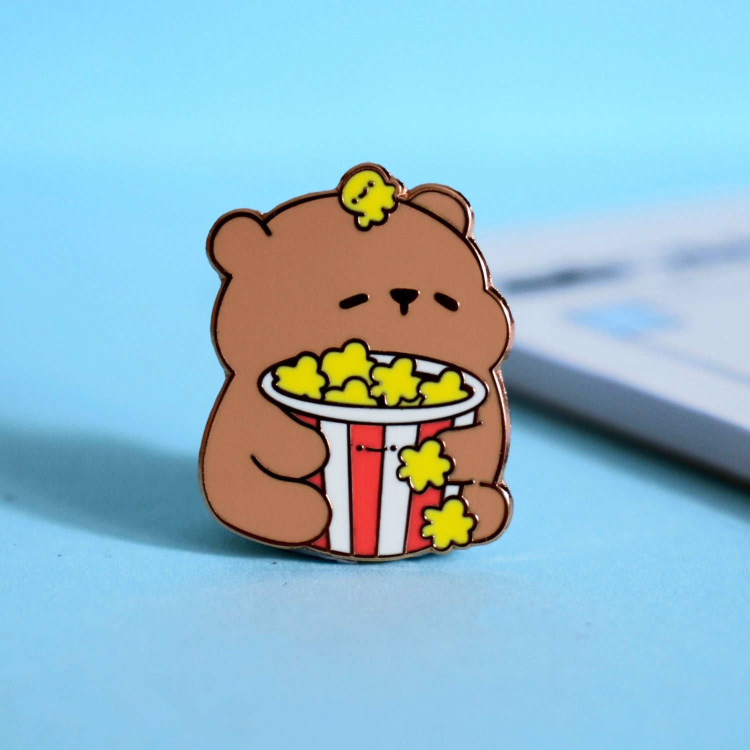 Bear with popcorn enamel pin on blue desk 