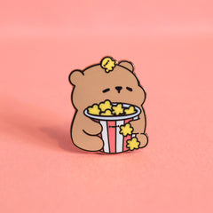 Bear with popcorn enamel pin on pink table 
