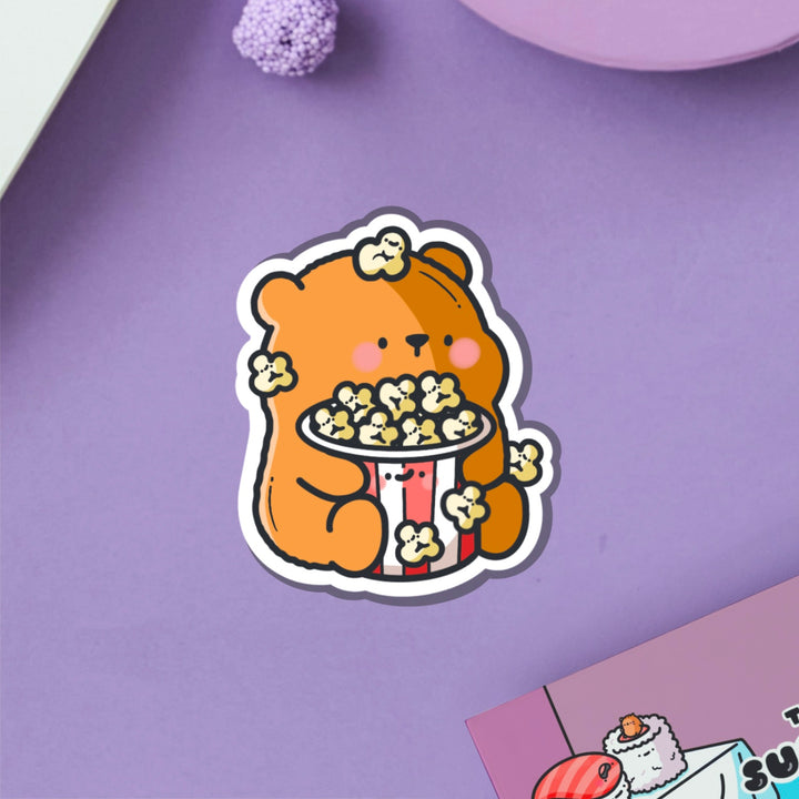 Bear with popcorn vinyl sticker on purple table