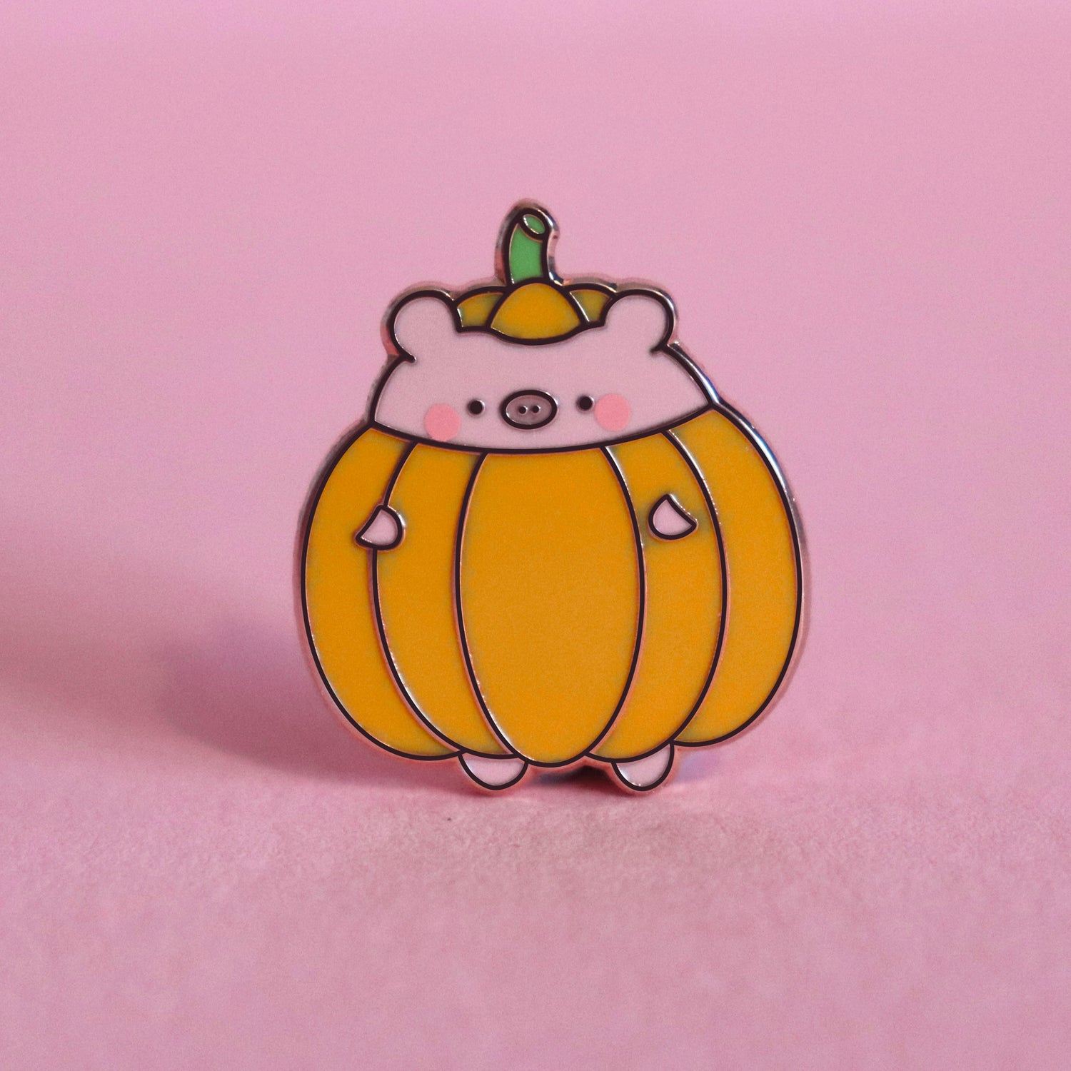 pig dressed as pumpkin enamel pin on pink table