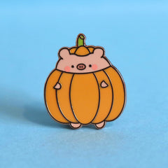 pig dressed as pumpkin enamel pin on blue desk